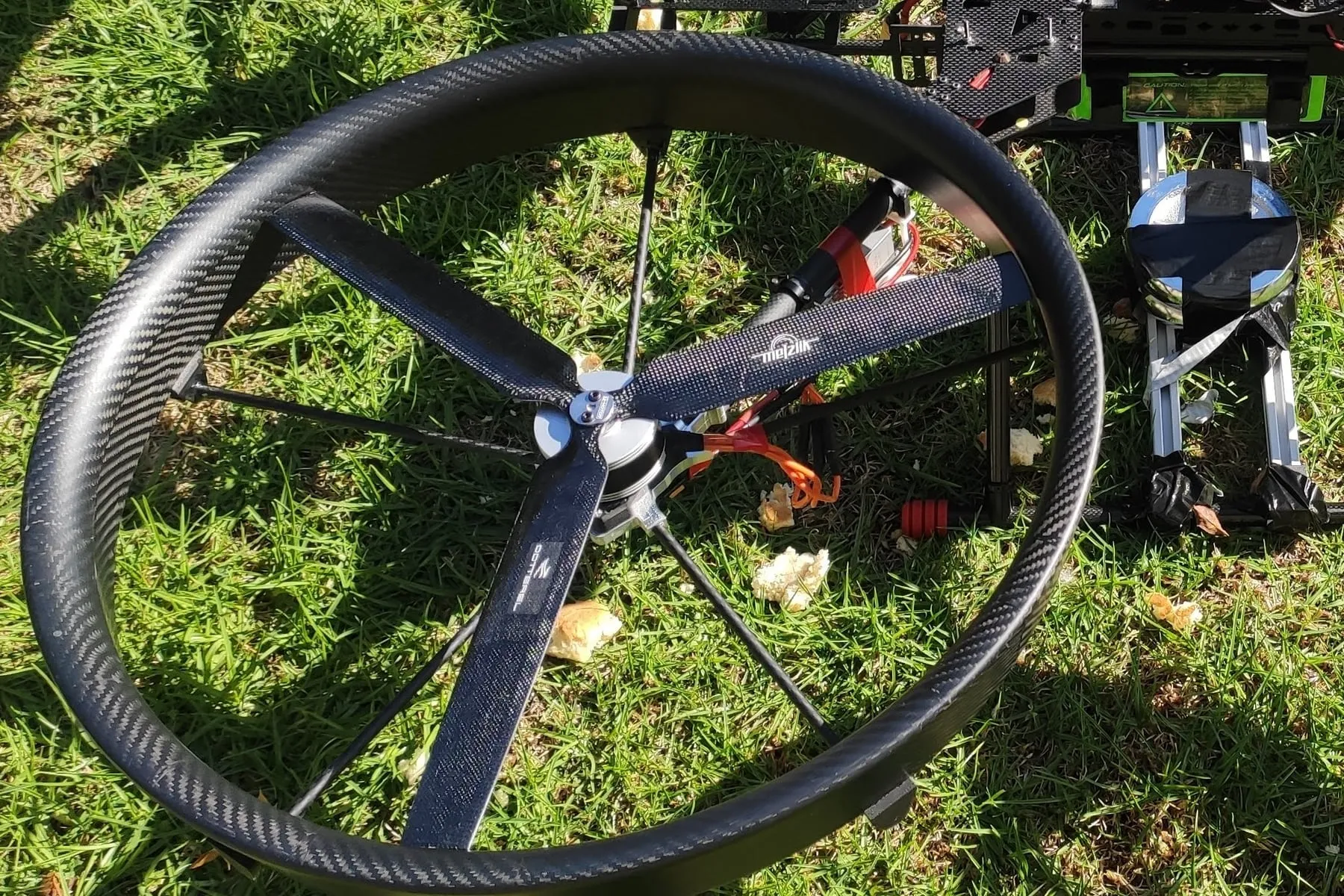 Custom blade inside a carbon fibre shroud on a quadcopter airframe, on grass during a weight test.